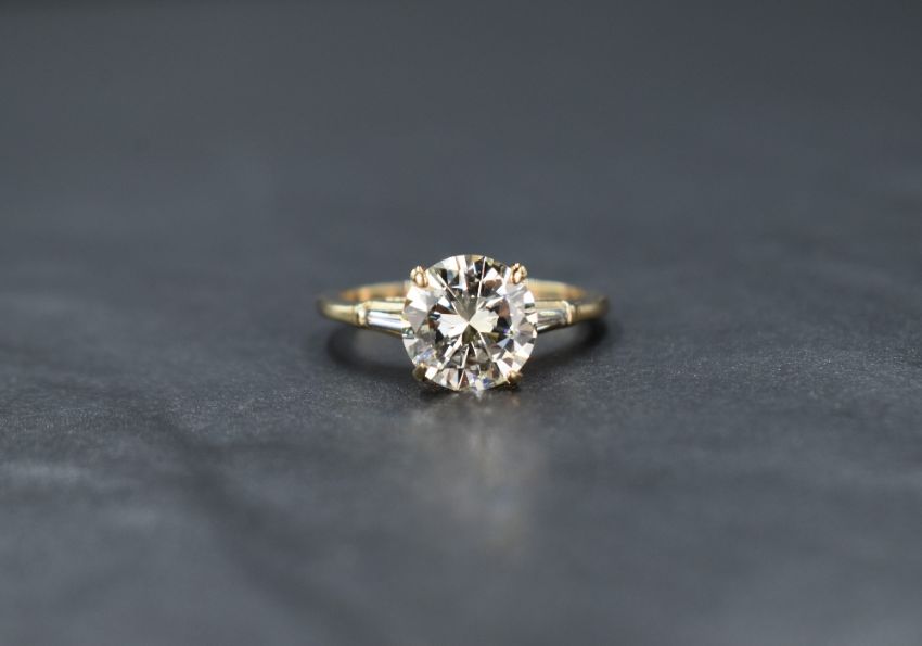 A 14ct gold diamond solitaire ring, the central round brilliant cut diamond measuring approximately 2.75ct, Colour M, Clarity VVS1, flanked by two tapered baguette cur diamonds measuring an approximate total of 0.25ct, colour J, clarity VVS, ring size P, 3.6g